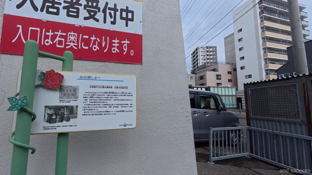 札幌市白石区にある「北海道庁立白石治療院跡・札幌市助産所跡」の歴史解説板。白黒の旧建物の写真と、沿革が詳しく書かれている。