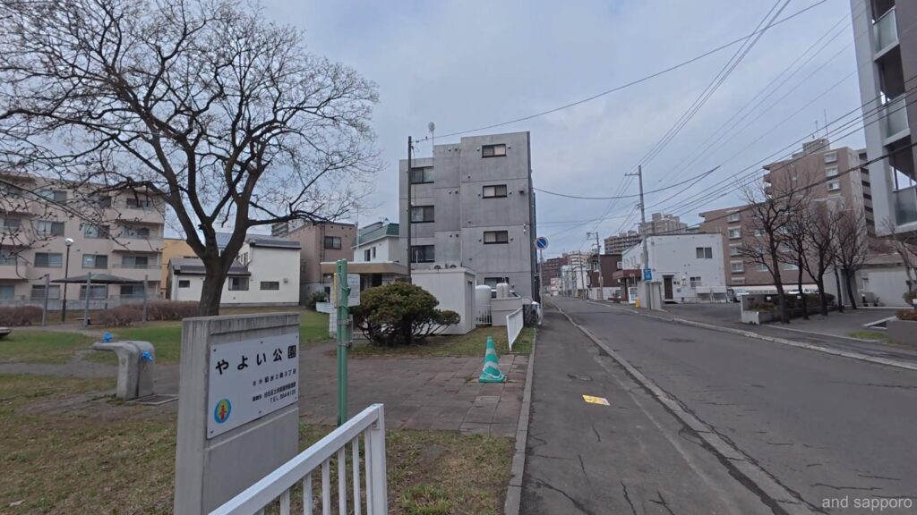 初春の淡い光が降り注ぐ「やよい公園」の広場。不自然に細長く続く空間が、かつてここに線路が並んでいた名残を感じさせる。